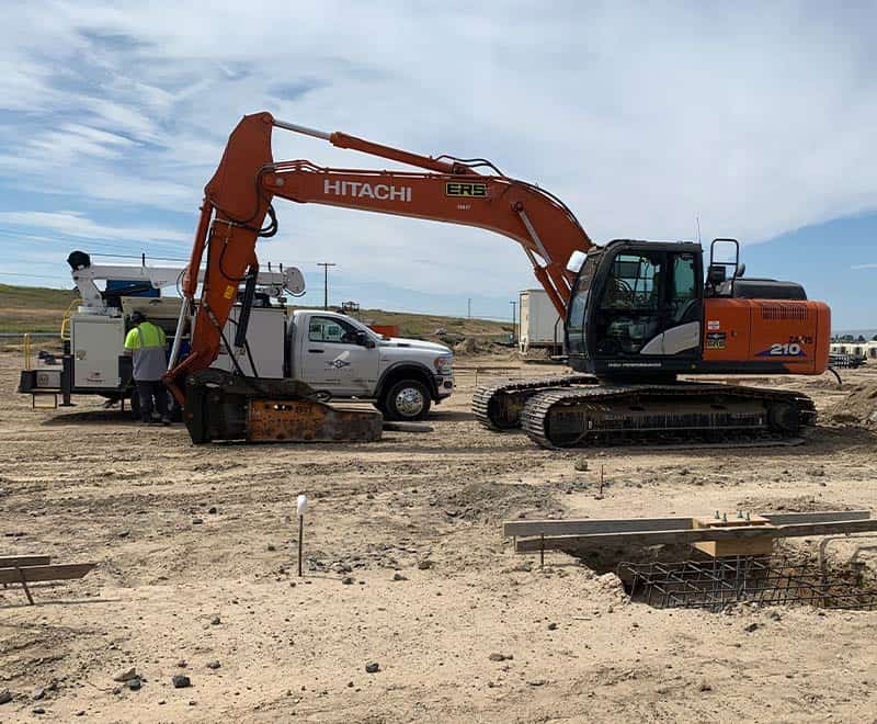 Excavator and construction workers at Moses Lake construction site.