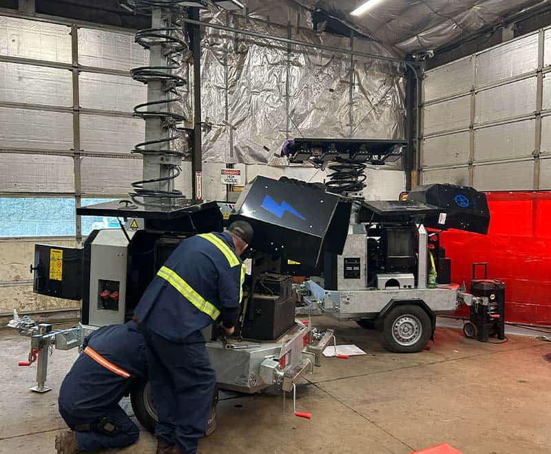 Technicians repairing large industrial machinery inside a warehouse.