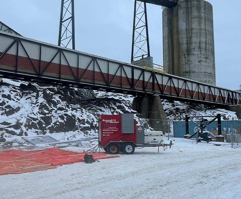 Industrial site with train bridge and snow-covered ground in Sudbury.