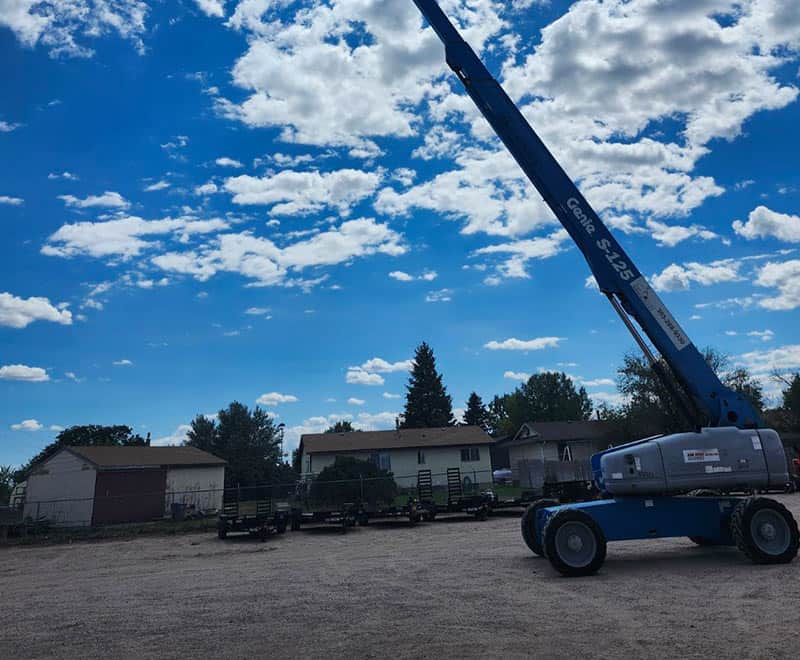 Construction crane at Wheatland rental property with blue sky and clouds.