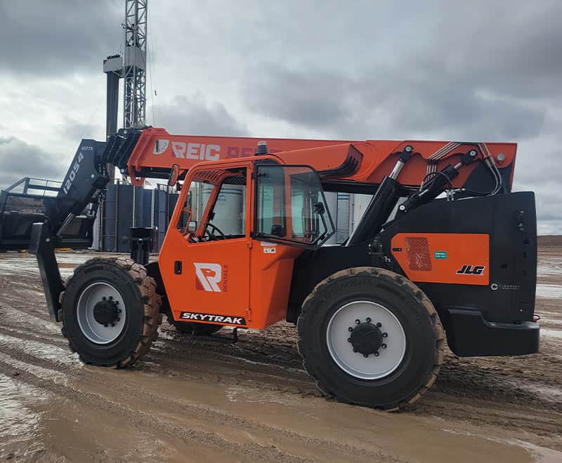 Orange REIC loader at construction site with cloudy sky.