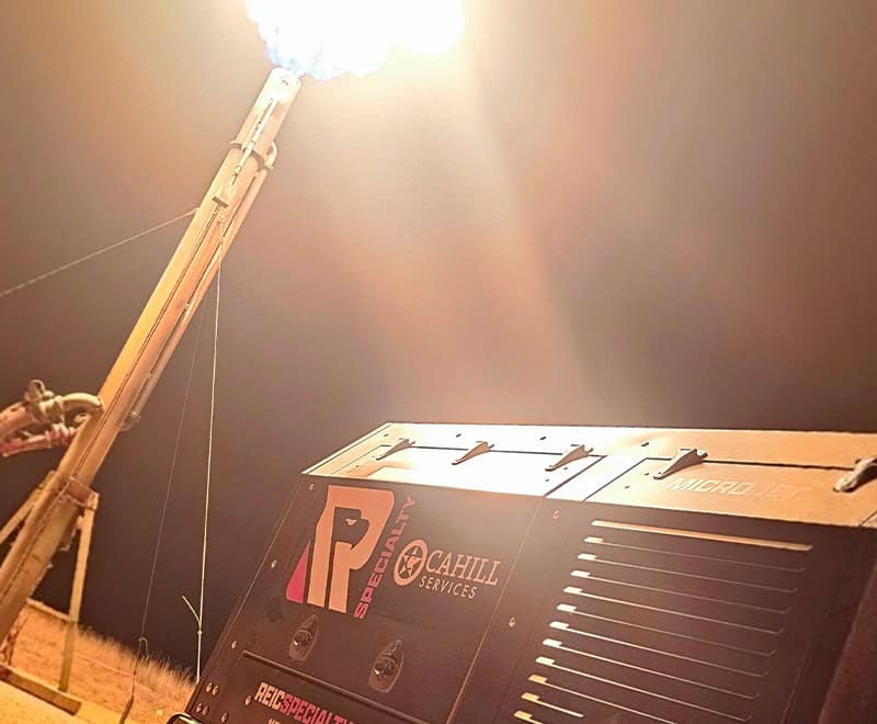 Nighttime image of REIC Rentals equipment with bright light overhead.