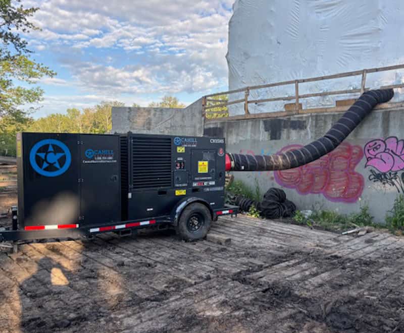 Portable generator on construction site with exhaust duct and graffiti wall.
