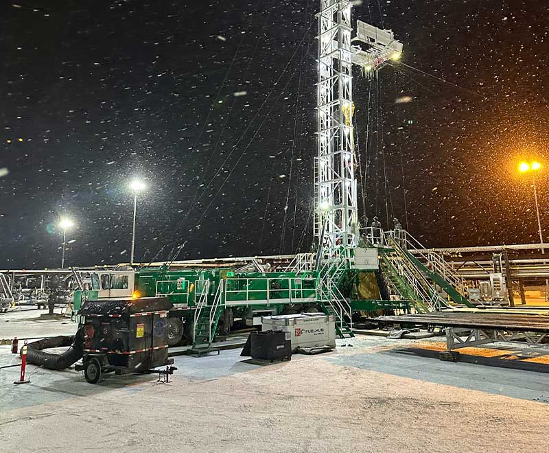 Oil rig in Red Deer during snowy night with snow falling and bright lighting.