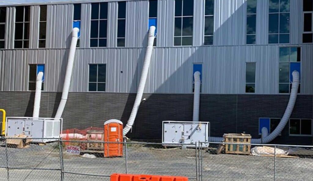 Construction site with large ventilation ducts on a modern building exterior.