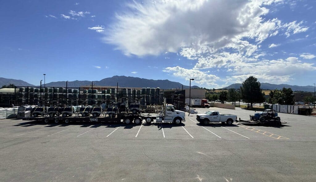 Large parking lot with trucks and cars under a partly cloudy sky.
