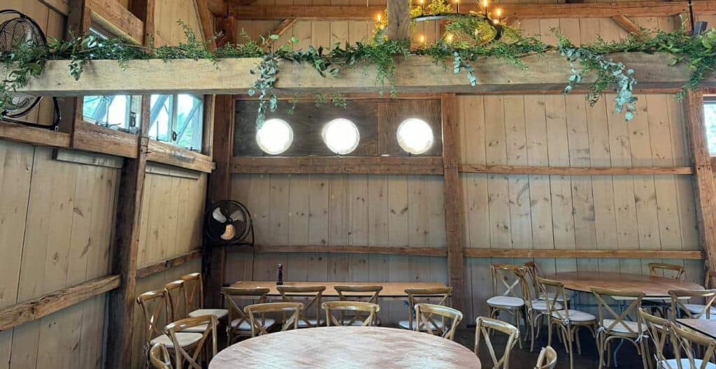 Rustic indoor event space with wooden walls and tables for gatherings.