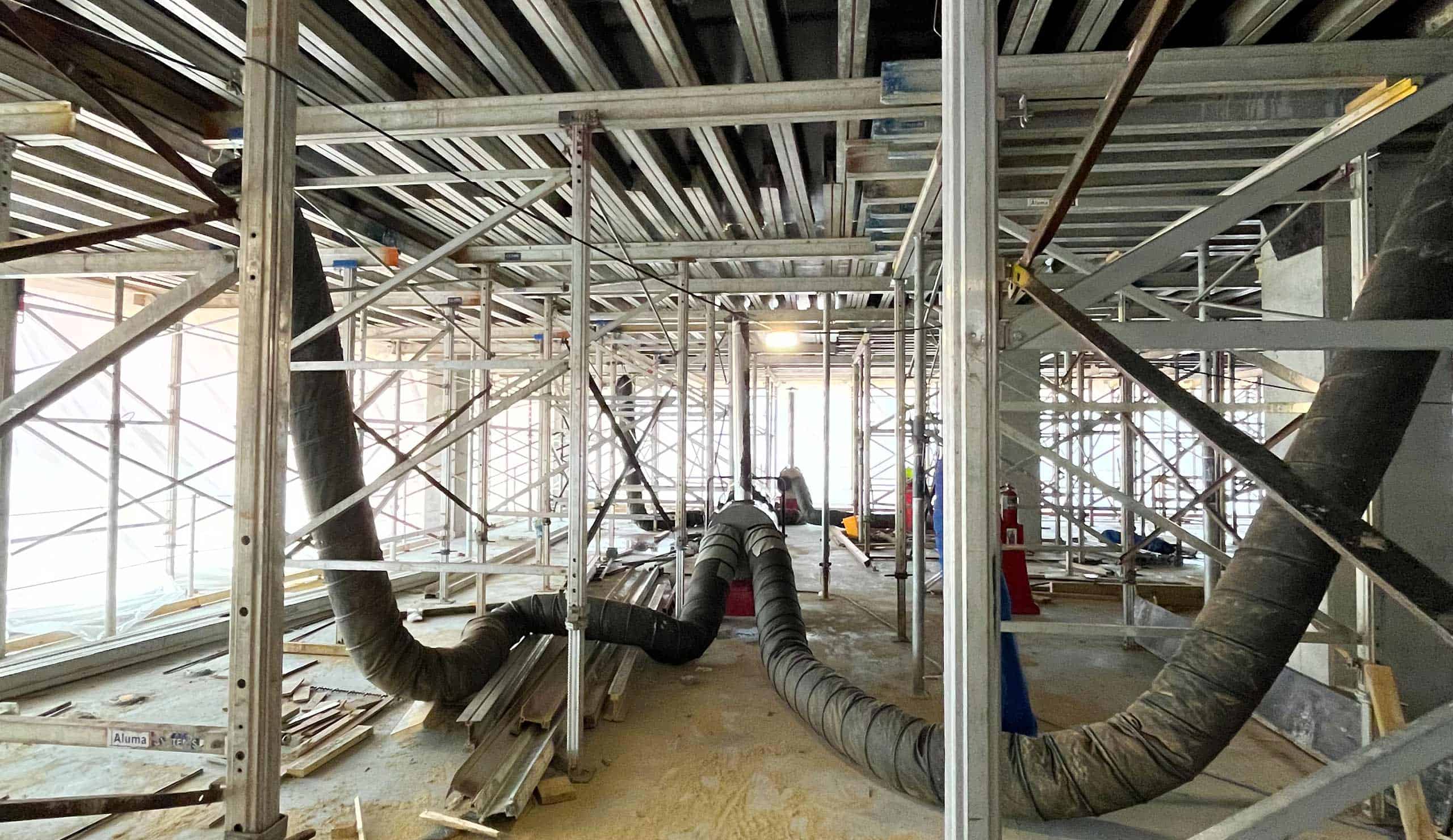 Construction site with HVAC ducts, scaffolding, and building framework.