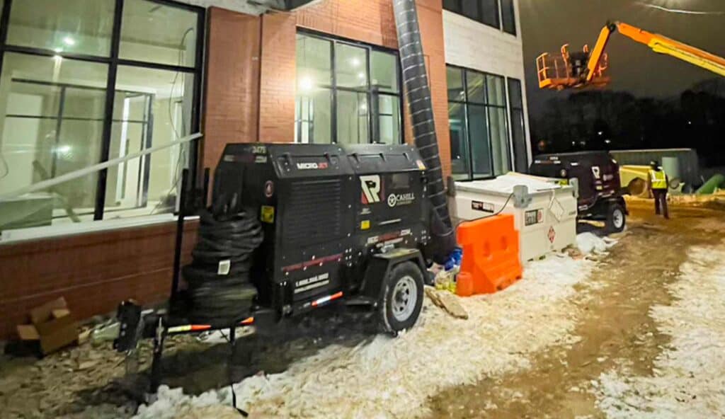 Construction equipment working outside a building during winter night.