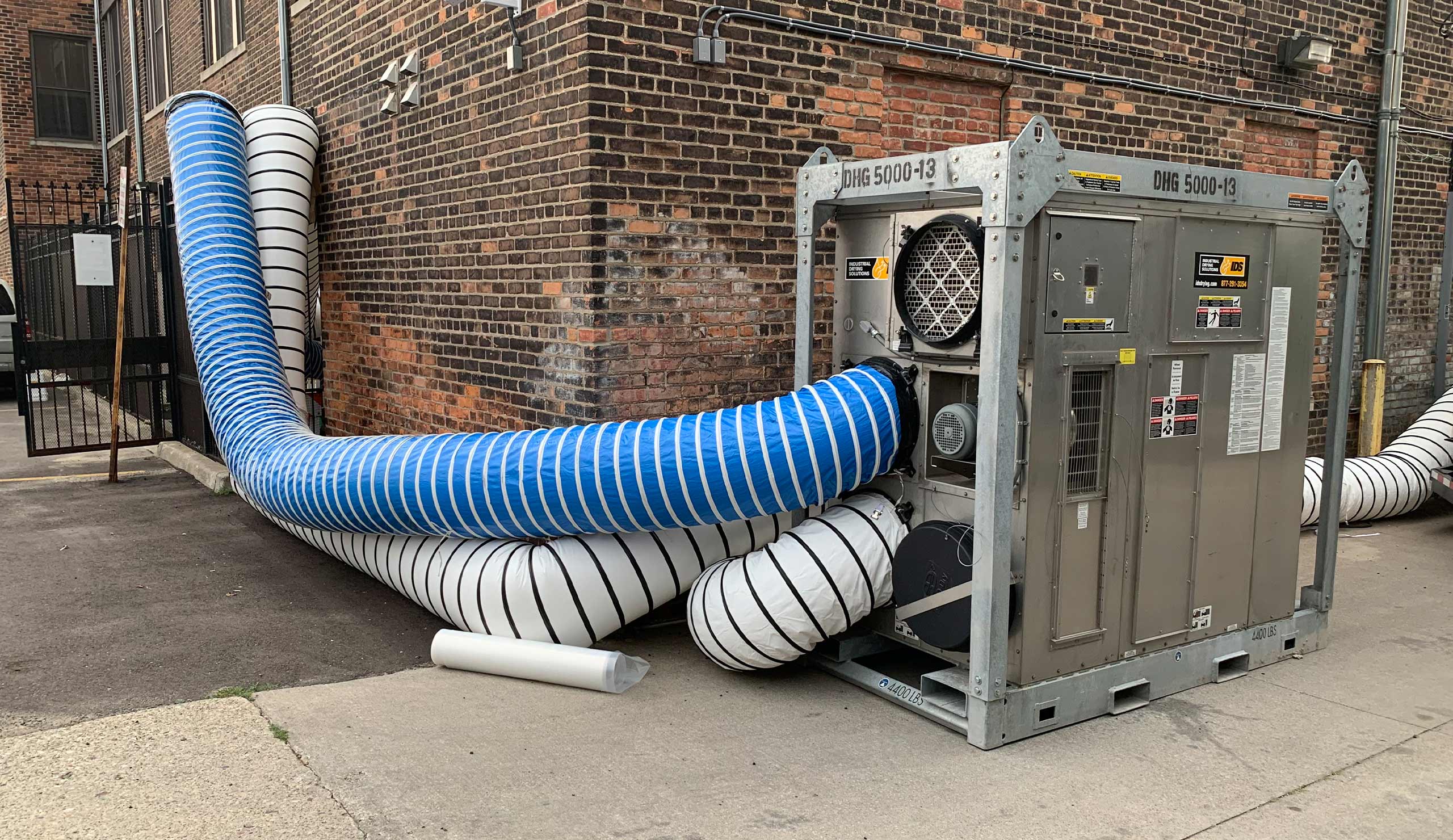 Large HVAC ventilation duct system outside brick building for moisture control.