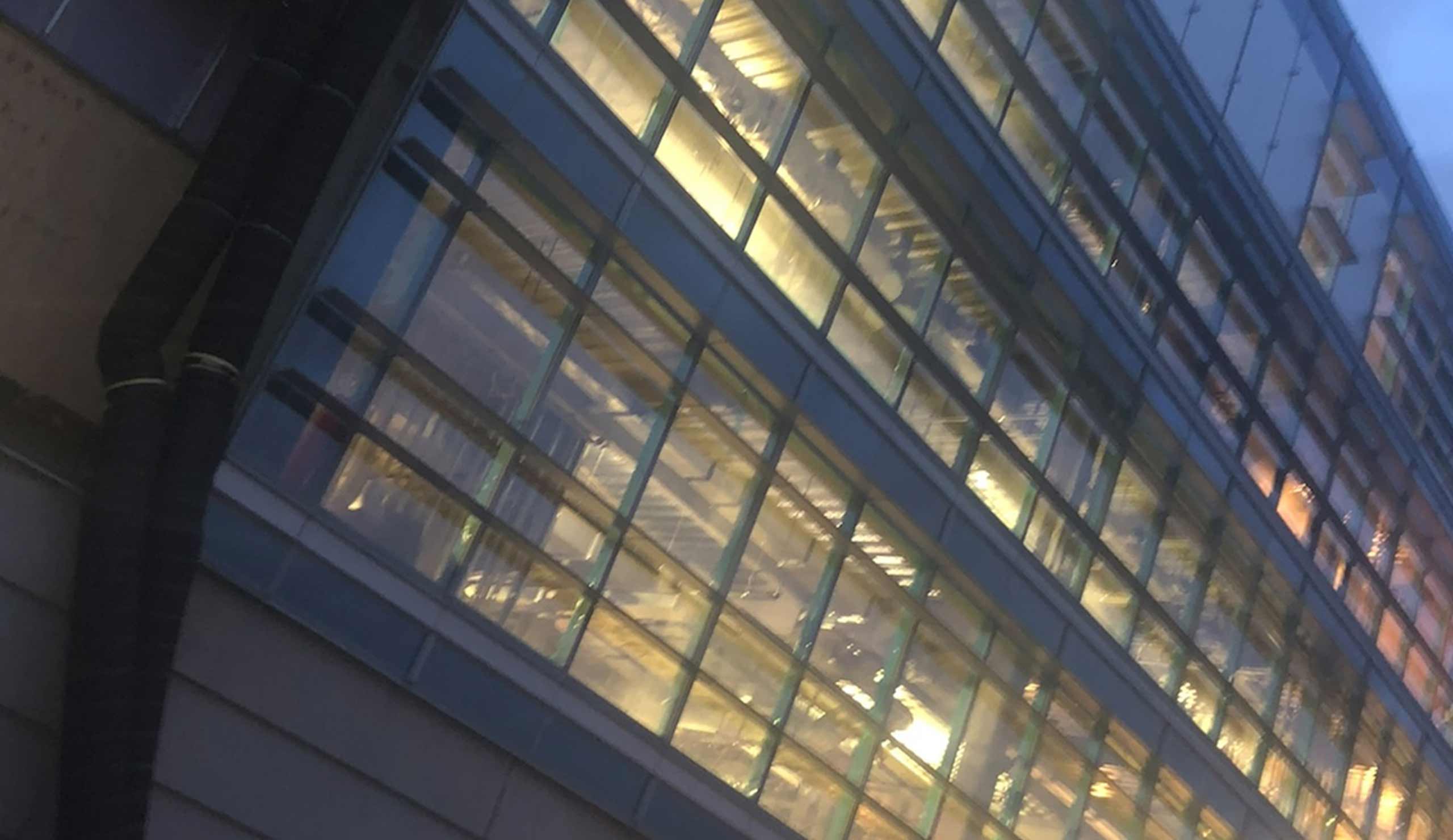 Contemporary glass building with illuminated interior at dusk.
