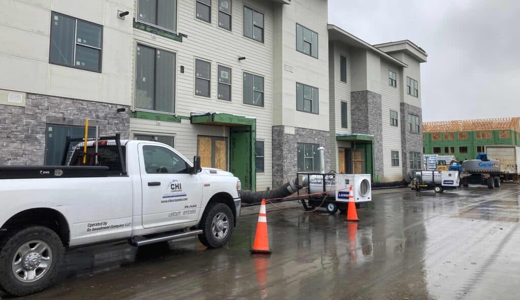 Construction site with HVAC units and trucks on a rainy day.