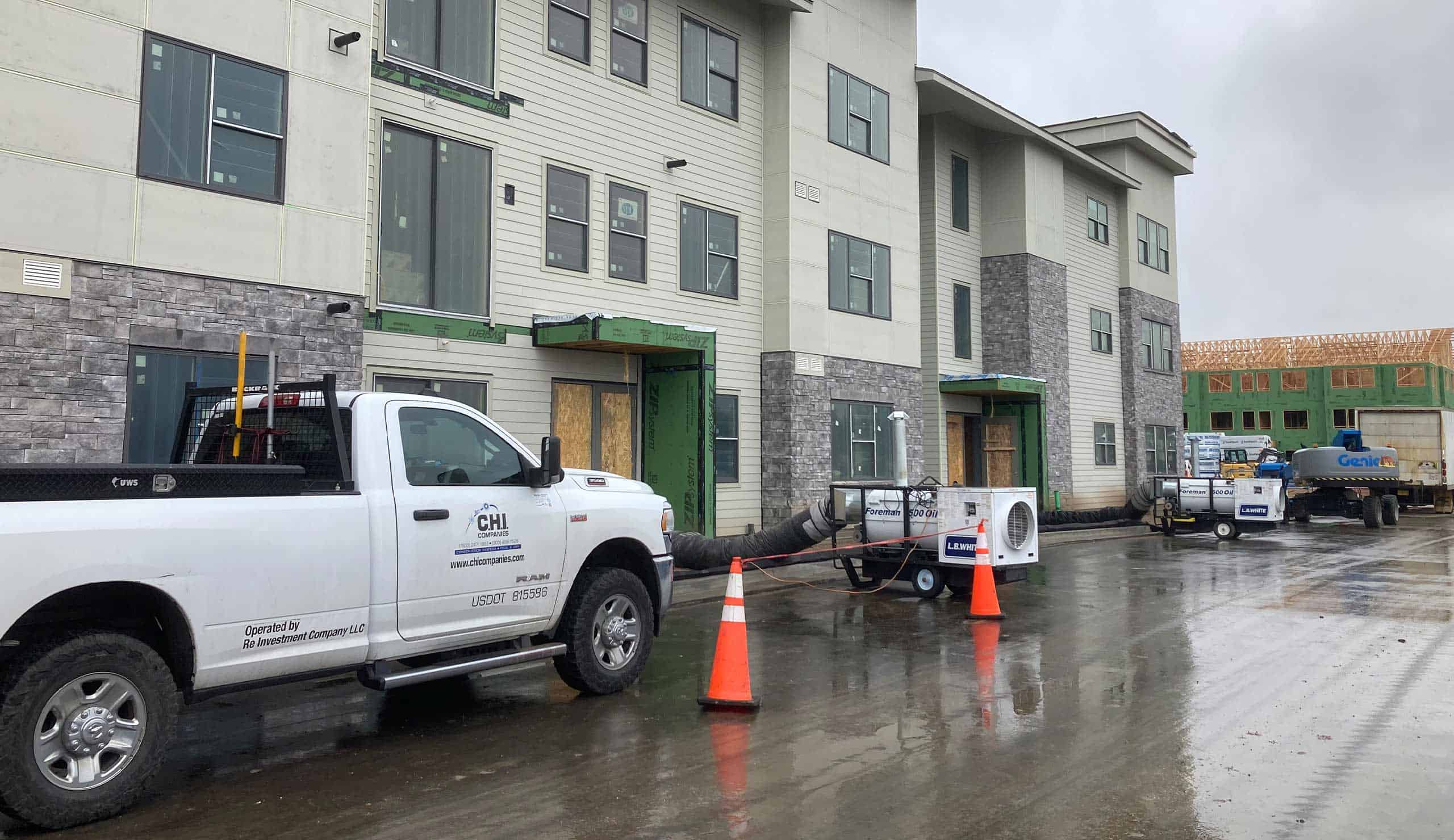 Construction site with HVAC units and trucks on a rainy day.
