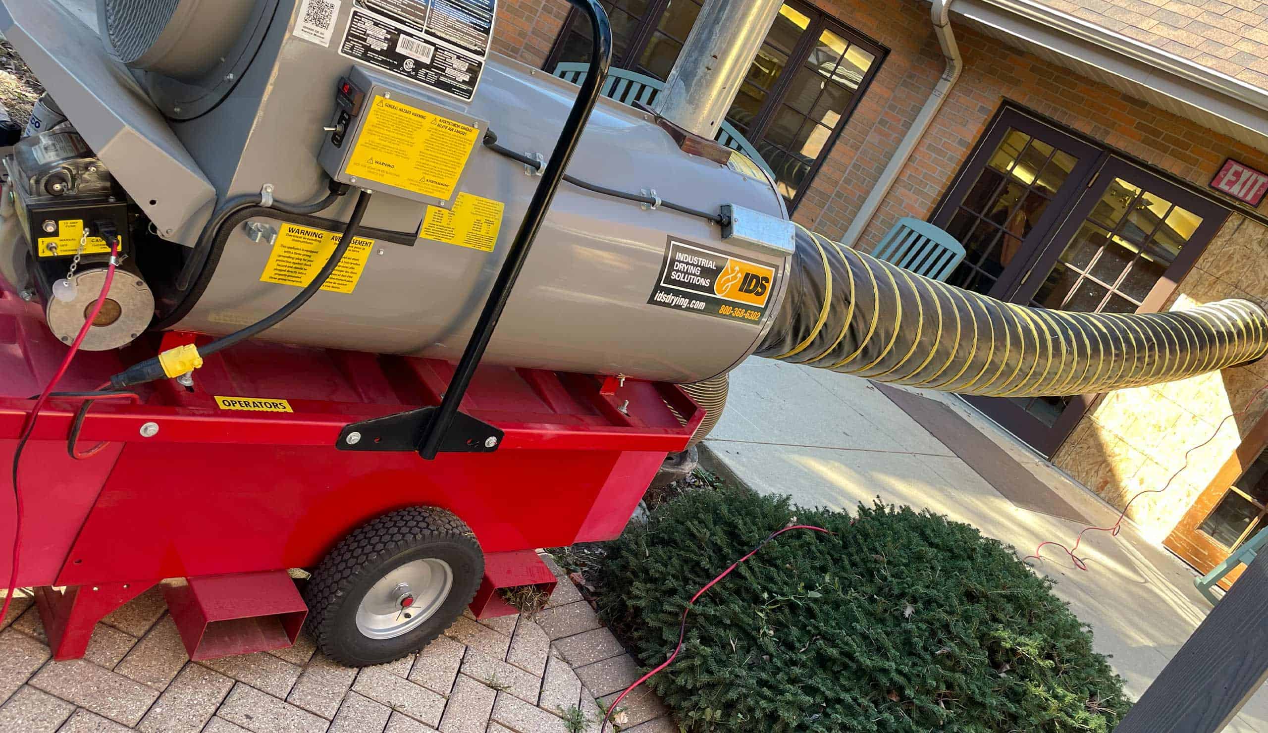 Portable HVAC rental unit external exhaust hose at hotel entrance.
