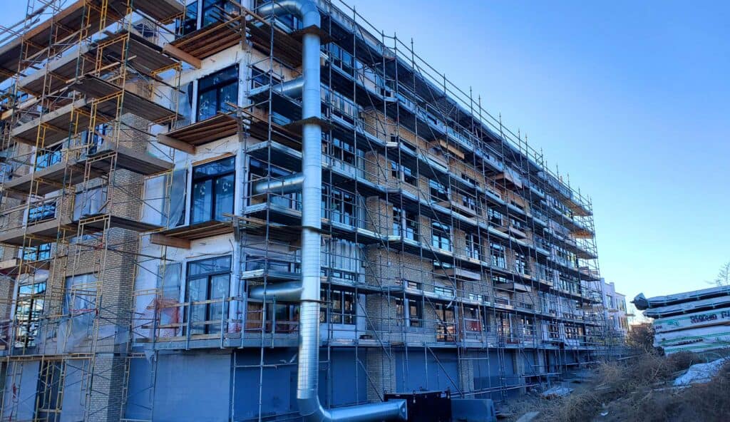 Scaffolding around a multi-story building under construction with metal pipes.