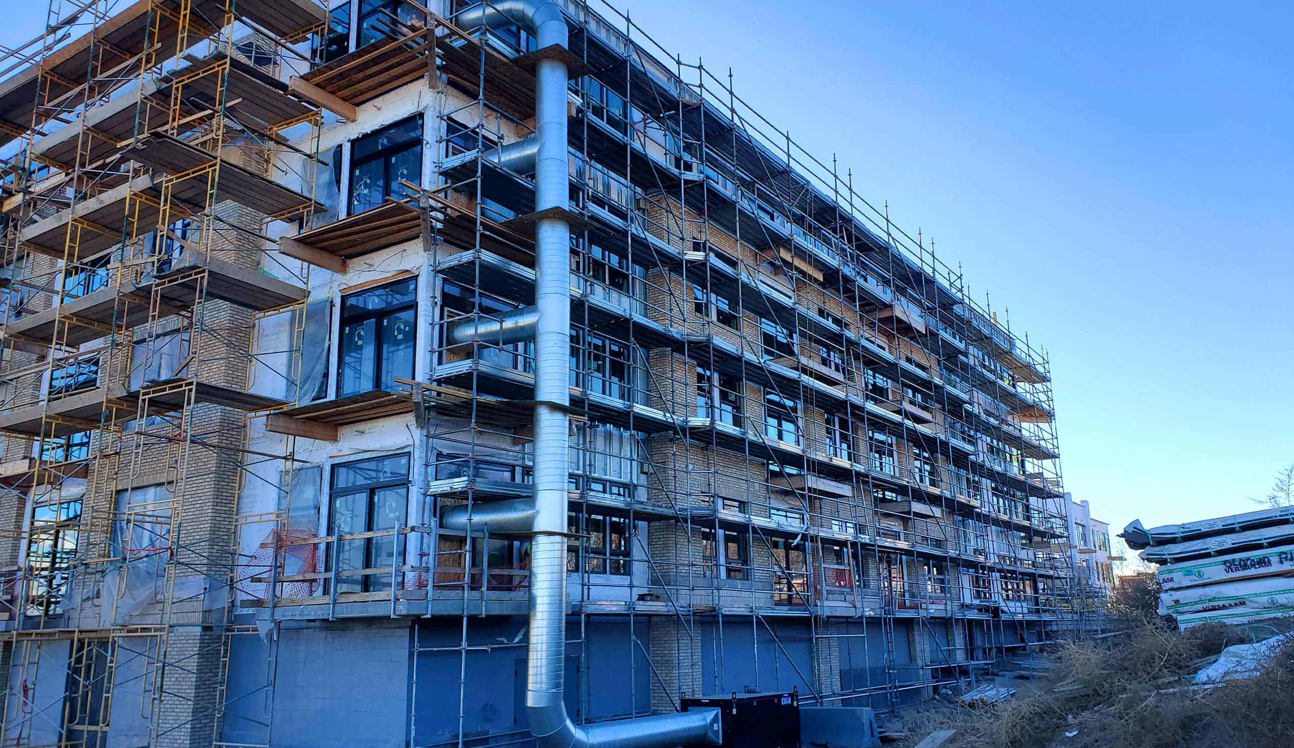 Scaffolding around a multi-story building under construction with metal pipes.