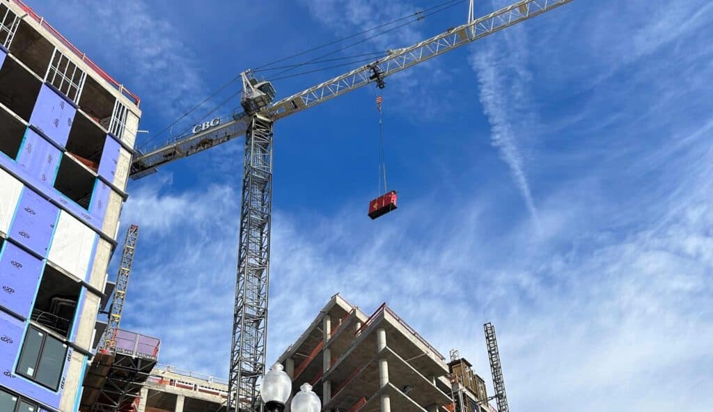 Construction site with crane and partially built building under blue sky.